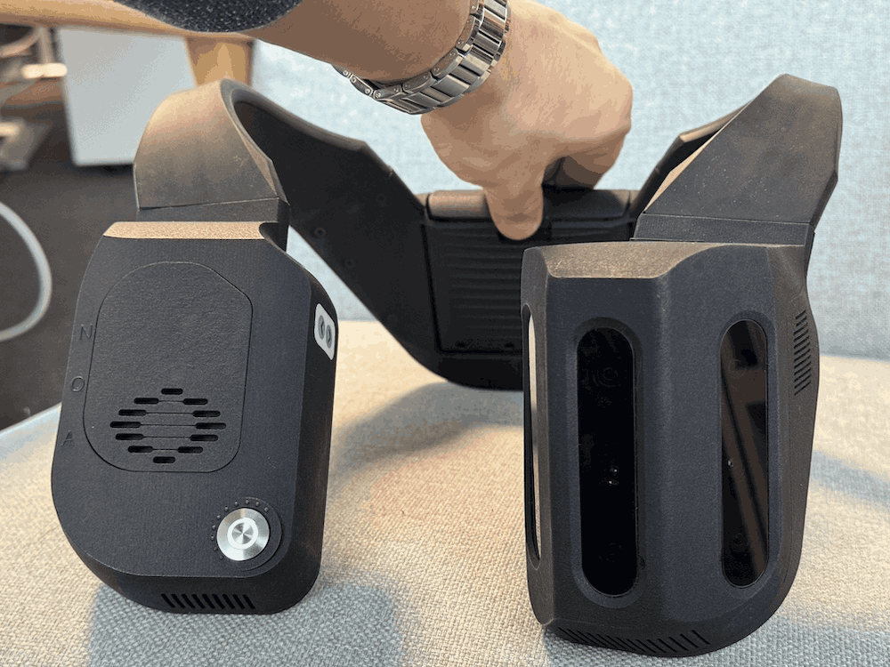 NOA device on a sofa with a hand sliding a battery inside the dedicated slot.